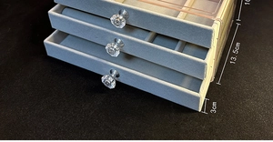 Three-layer clear acrylic jewelry box with grey velvet lining and crystal drawer handles