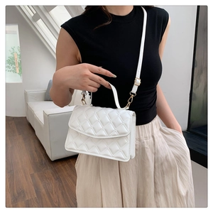 Close-up of white quilted leather crossbody bag with elegant gold metal hardware