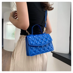 Bright blue quilted crossbody bag with gold hardware worn by a model in natural light