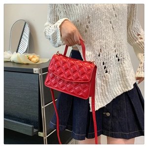 Detail shot of bright red quilted leather handbag with chic chain strap and top handle