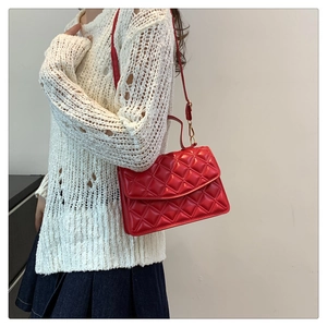 Side view of red quilted leather crossbody bag with chain strap on a white sweater