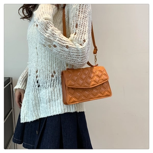 Classic orange quilted flap bag worn by model with adjustable leather shoulder strap
