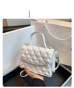 Close-up of white quilted crossbody bag with gold turn-lock and elegant chain strap