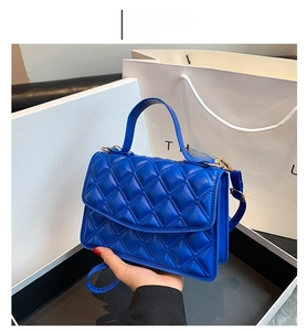 Close-up of blue quilted leather crossbody bag with top handle and matching strap