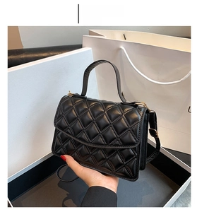 Detail of black quilted shoulder bag featuring gold hardware and elegant chain strap