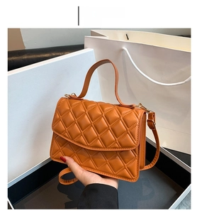 Close-up of brown quilted faux leather handbag with stitching detail and gift packaging