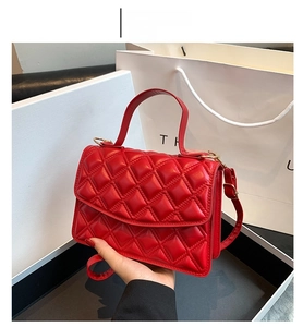 Detail of a red quilted shoulder bag with matching strap and elegant flip cover