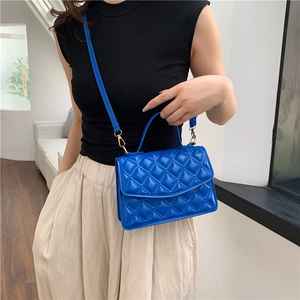 Royal blue quilted crossbody bag with gold hardware and top handle shown on model