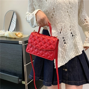 Chic red quilted crossbody bag with gold hardware and top handle shown on a model