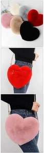 Detailed view of heart-shaped faux rabbit fur crossbody bags with gold chain straps in multiple colors