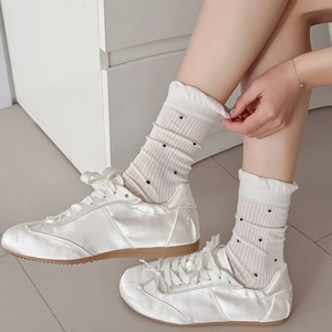 White silk sneakers paired with mesh polka dot crew socks featuring lettuce trim cuff