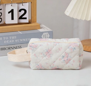 Detailed close-up of quilted floral cosmetic bag with blue flowers and woven handle strap
