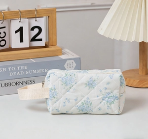Detail of blue floral quilted cosmetic bag with ribbon handle in cozy room setting