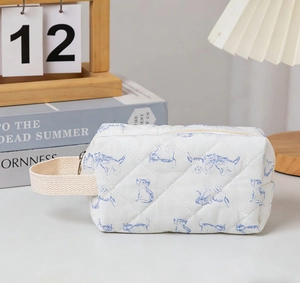 Close-up of quilted floral makeup bag featuring blue cat prints and soft fabric texture
