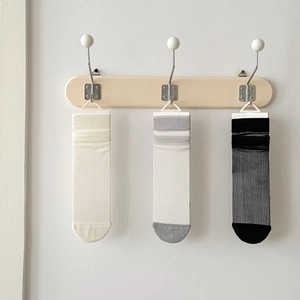 Three pairs of breathable mesh crew socks in cream, grey, and black on wooden hangers