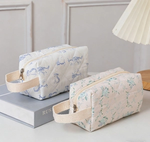 Detailed close-up of quilted cotton floral and cat pattern toiletry bags with handles