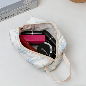 Quilted floral makeup bag with blue flower patterns and zipper closure in a soft cream color