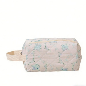 Quilted floral makeup bag with blue flower pattern and side handle for travel storage