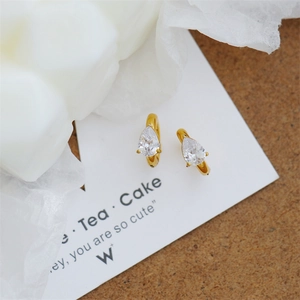 Detailed close-up of golden clip-on earrings with pear-shaped cubic zirconia crystals