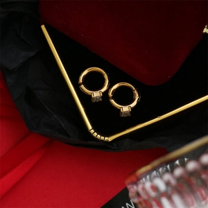Macro shot of gold hoop earrings with square cubic zirconia pendants on black display