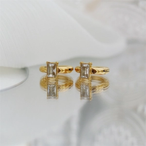 Minimalist gold square crystal ear clips with polished finish on reflective surface