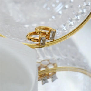 Detail of adjustable gold ring earrings with rectangular zircons on glass edge