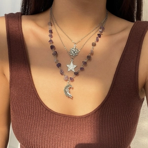 Detailed close-up of layered necklace set featuring purple stone beads and moon charms