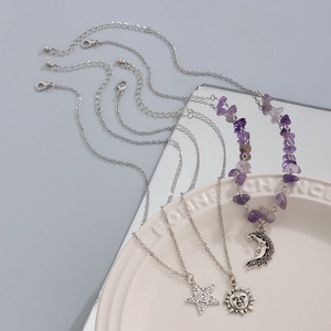 Detailed view of layered necklaces set with amethyst stones and celestial pendants