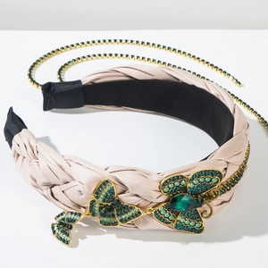 Detail eines rosa geflochtenen Leder-Stirnbands mit goldenen Schmetterlings-Anhängern