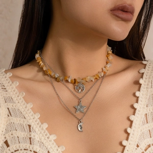 Close-up of bohemian layered necklace with crushed stones, tree of life and moon charms