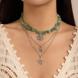 Close-up of triple-layered silver necklace with green stones, sun, moon and star pendants