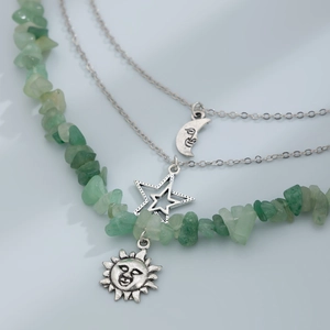 Detail of layered bohemian necklace with green gravel stones and silver moon star pendants