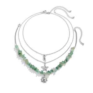 Detailed view of triple-layered necklace with moon, star, and sun charms with green stones