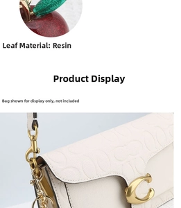 Detail of red glitter apple keychain with resin leaves on a white coach handbag