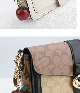 Close-up of leather handbag details with a sparkling red apple-shaped keychain accessory