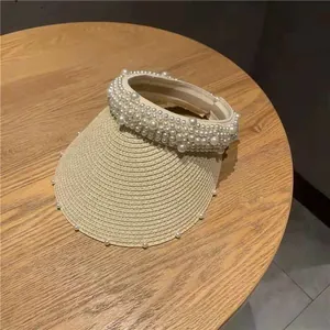 Detailed top view of a straw sun hat featuring elegant white pearl embellishments