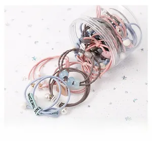 Detail of colorful elastic hair ties set with pearls and ribbons in a clear jar