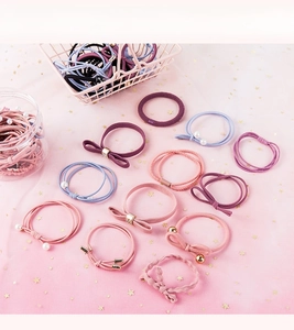 Detail of high-elasticity hair ties with bows, pearls and metal charms in soft pastel tones