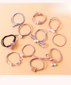 Pink elastic hair ties set with pearl and flower accents shown in a flat lay detail