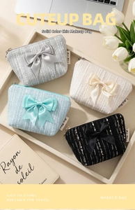 Close-up of tweed mini pouches with large silk bows and zipper in four elegant colors