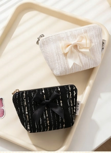 Close-up of elegant bow mini purses with gold zippers in cream and black colors