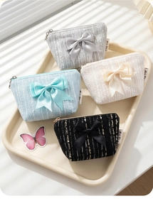 Detail of four tweed coin purses with large bows in grey, blue, white, and black colors