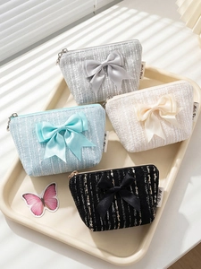 Chic tweed mini bow purses in four pastel colors displayed on a cream tray with light shadows