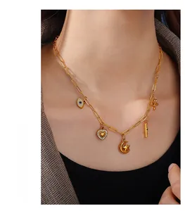 Detail of gold paperclip chain necklace featuring heart, star and evil eye charms on a model
