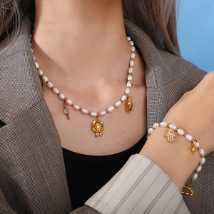 Baroque pearl jewelry set with gold heart lock and hamsa hand charms on a model