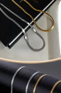 Macro shot of 3mm gold and silver stainless steel flat snake chains on textured background