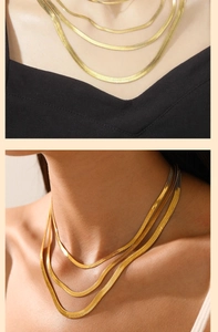 Macro detail of layered gold herringbone chains showing flat texture and metallic luster