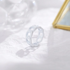 Close-up of a white chain-link open ring with a matte finish on a textured paper background