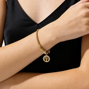 Detailed view of a gold tree of life pendant bracelet with zircon stones on wrist