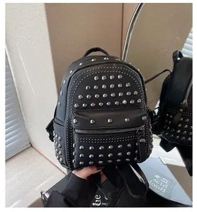 Detail of black pebbled leather mini backpack with silver punk studs and mirror reflection